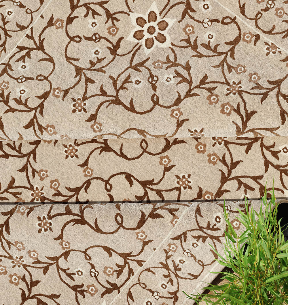 The RAMSHA HOME Exquisite Multi Color Decor Handmade Rug - HTW 99 (300x400 CM) is a beige hand-tufted wool rug with embroidered brown floral and vine patterns, and a green leaf cluster in the bottom right corner.