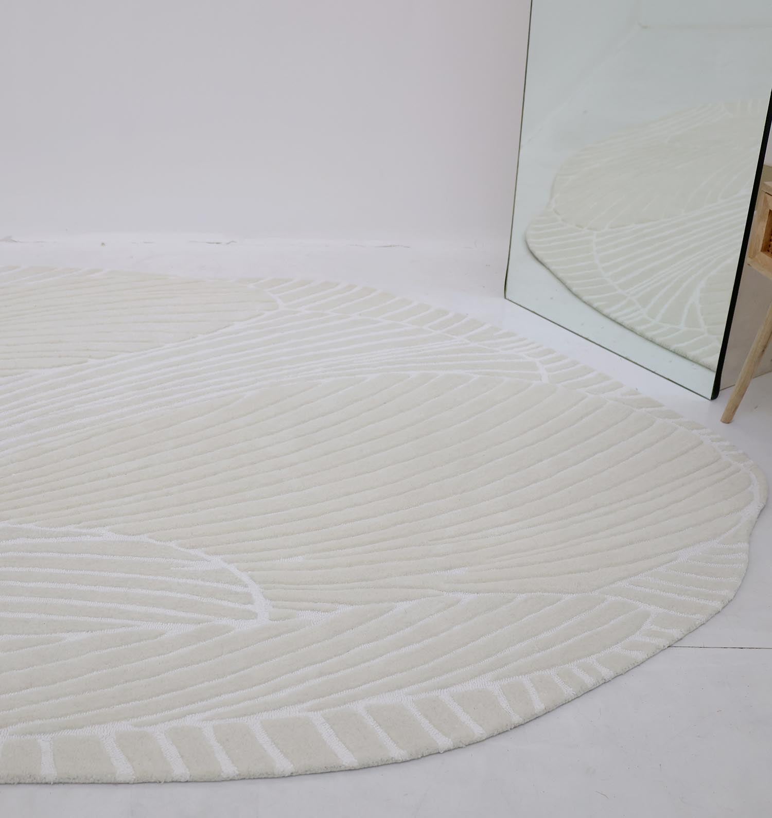 The RAMSHA HOME Handmade Carpet 200x300 cm Shaped Area rug HTWV-103 with curved, leaf-like patterns is placed on a white floor beside a large mirror reflecting part of the rug and a wooden chair.