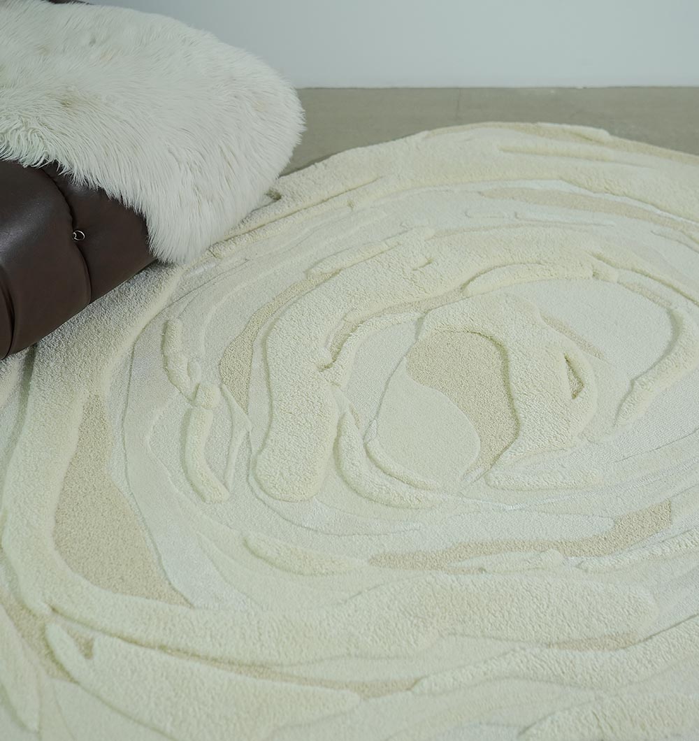 A Beige Color Oval Shaped Handmade Rug - HTWV 106 (200x300cm) by RAMSHA HOME lies on the floor next to a brown leather sofa with a white, fluffy throw.