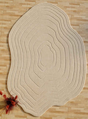 The RAMSHA HOME Hand Tufted Beige Color Decor Rug HTWV-108, with textured contour lines, rests on a light wood floor. A small red dried flower arrangement in the corner adds a vibrant accent to this modern wool Tencel rug.