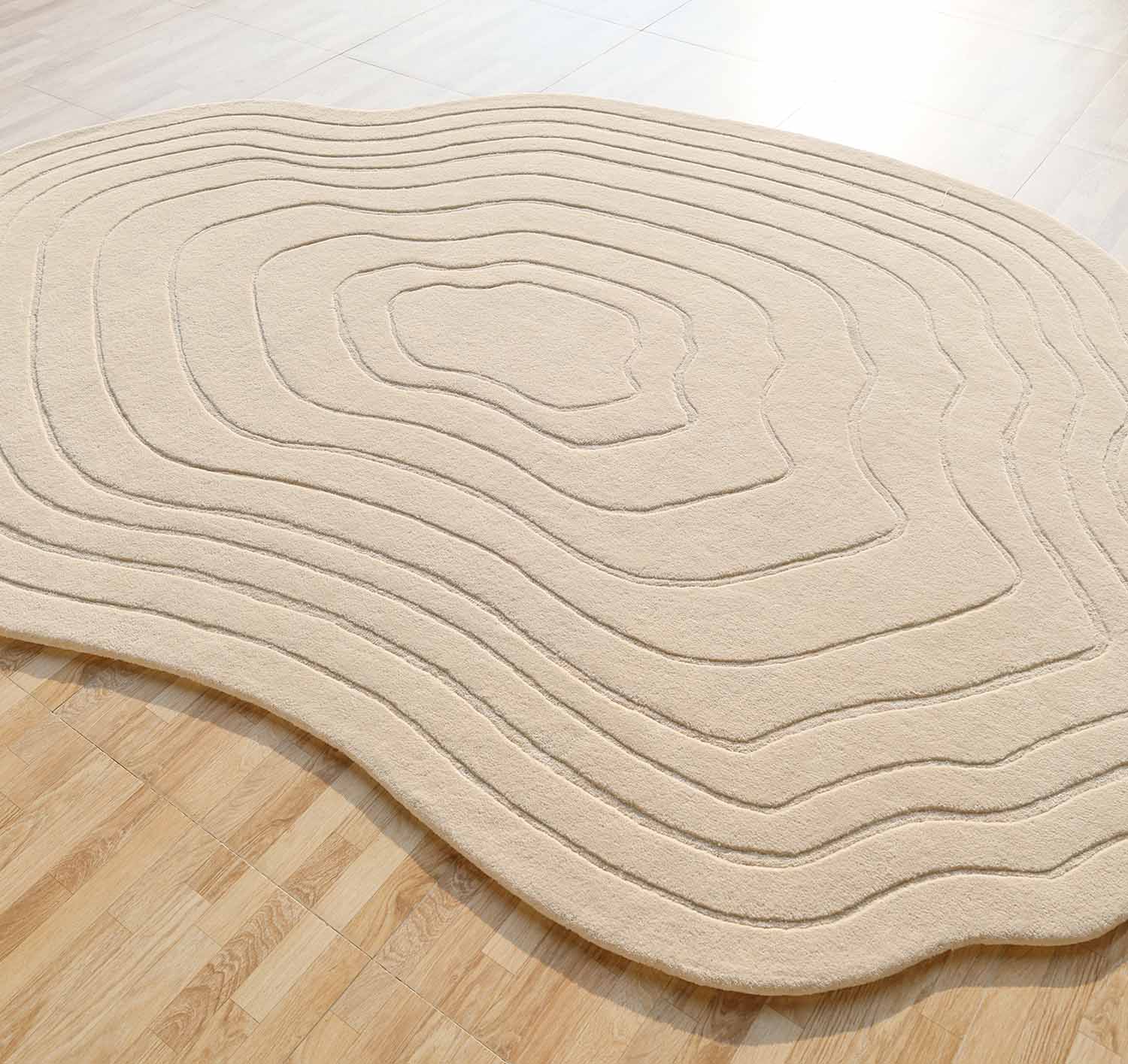 The Hand Tufted Beige Color Decor Rug HTWV-108 by RAMSHA HOME features an irregular shape and raised, contour-like lines inspired by topographic maps, bringing modern texture to light wooden floors.