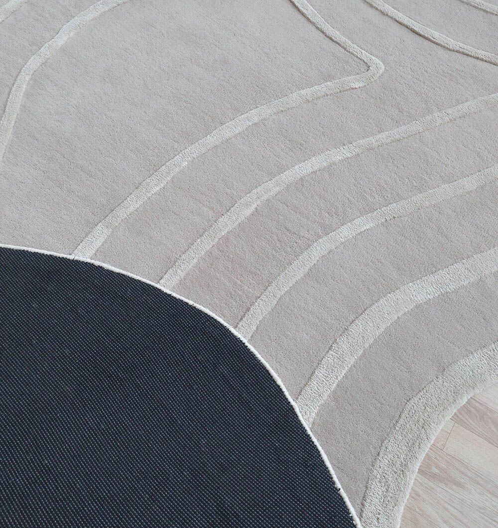 The Beautiful Off White Handmade Rug - HTWV-112 (200x300cm) by RAMSHA HOME features abstract grey contours, a beige background, raised wavy lines, and a bold black semicircle. This hand-tufted rug is displayed on a light wooden floor.