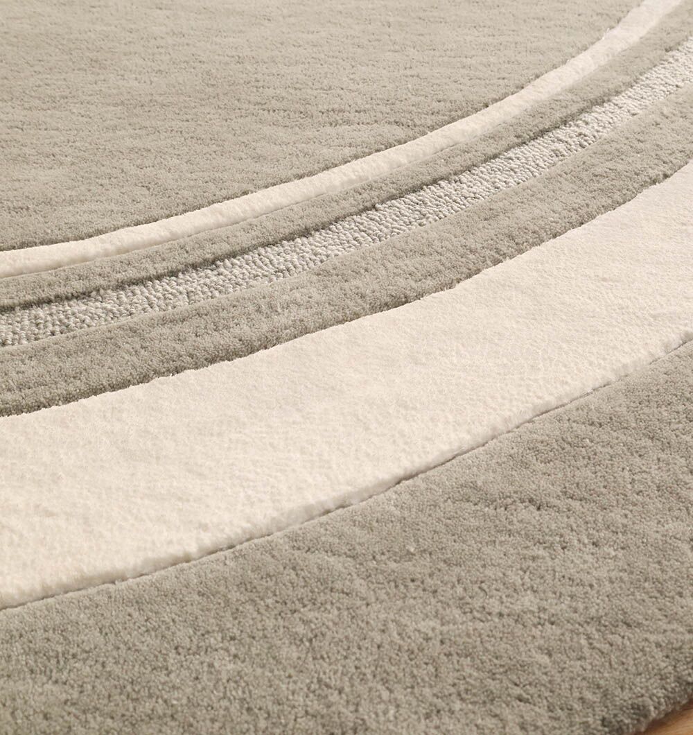 Close-up of the RAMSHA HOME Grey & White Color Round Handmade Rug (HTWV-121), a handtufted wool rug with curved, overlapping bands in light gray and off-white, featuring a soft, plush surface.