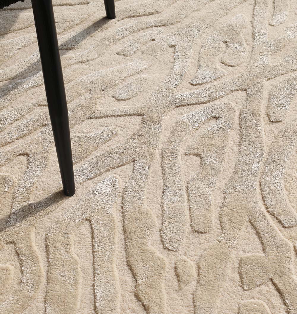 Close-up of the RAMSHA HOME Natural White Color Handmade Area Rug (HTWV-130), crafted from a wool viscose blend with raised, abstract patterns. A single black chair leg appears partially on the left side.