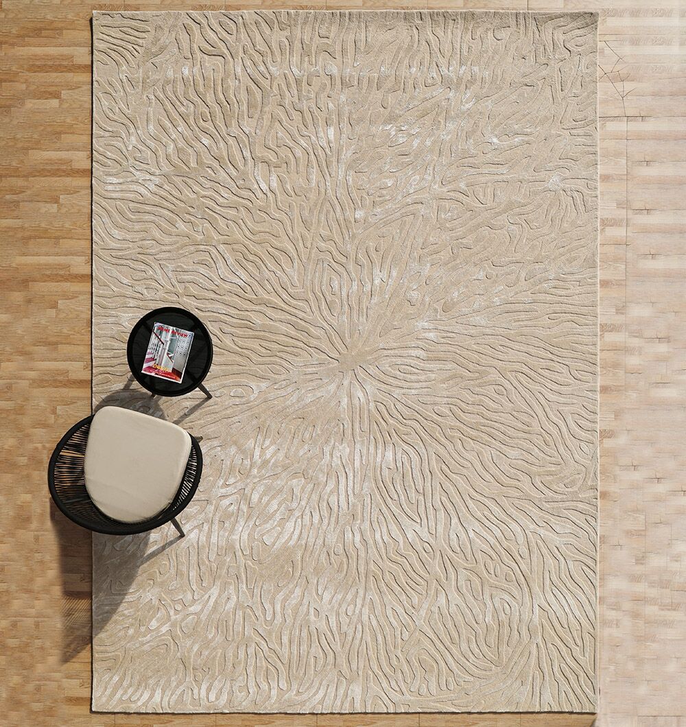 The RAMSHA HOME Natural White Color Handmade Area Rug - HTWV-130, handtufted in wool and viscose with wavy patterns, lies on a wooden floor, complemented by a black round side table and a light cushioned chair.