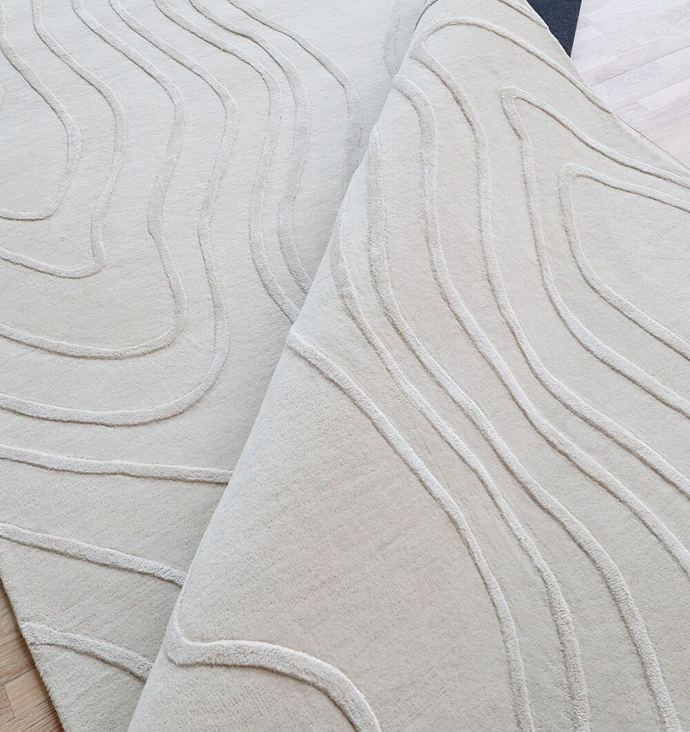 Two Multi Color Handmade Area Rugs (HTWV-133) by RAMSHA HOME, with raised wavy line patterns, overlap on a light wood floor for a subtle textured look.