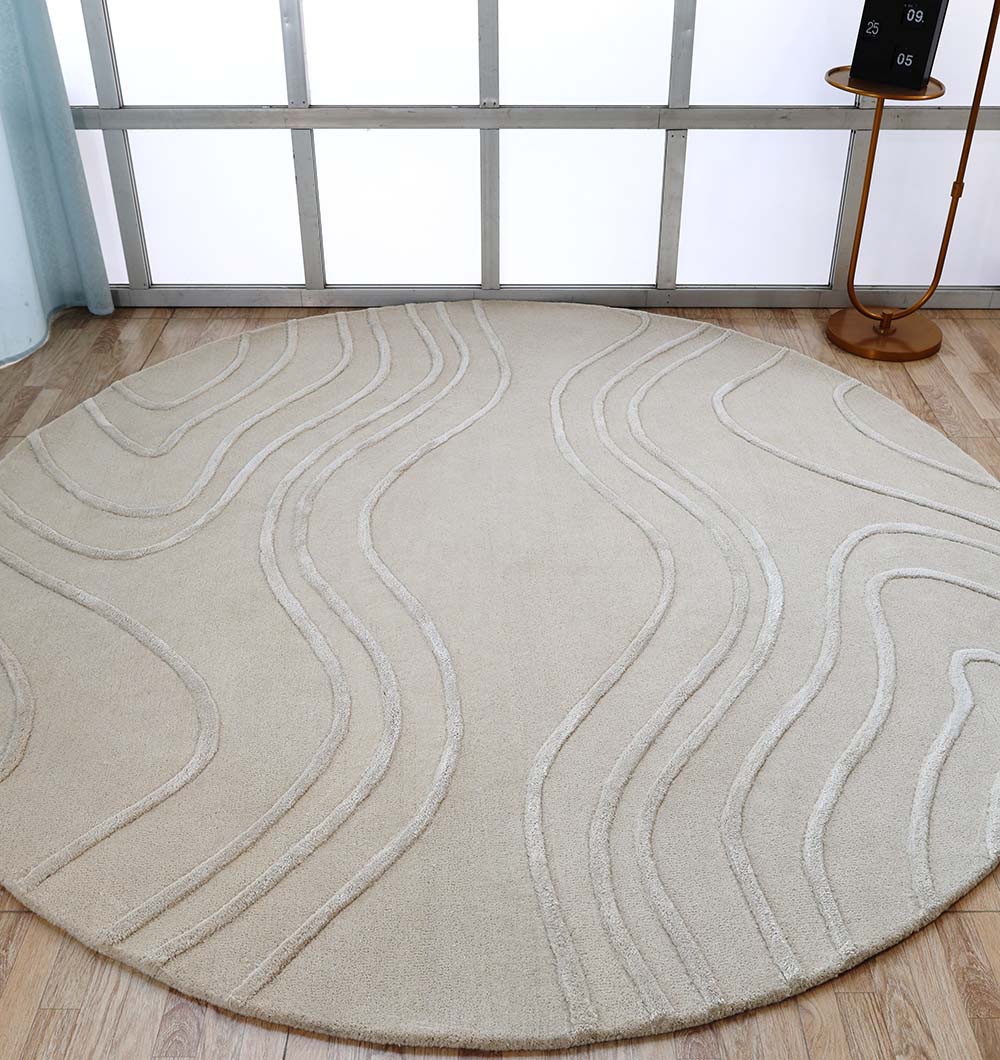 The RAMSHA HOME Multi Color Handmade Area Rug - HTWV-133, a large round wool piece with raised wavy lines, sits on a wooden floor by a window next to a small round table in a bright room filled with diffused natural light.