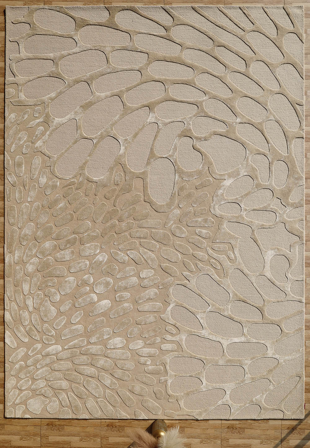 The RAMSHA HOME Organic Flow Hand-Tufted Rug – Soothing Beige Textured Elegance HTWV-134 features an abstract pebble pattern and is shown on a wooden floor, with a fluffy accent and a gold pole at the bottom edge.
