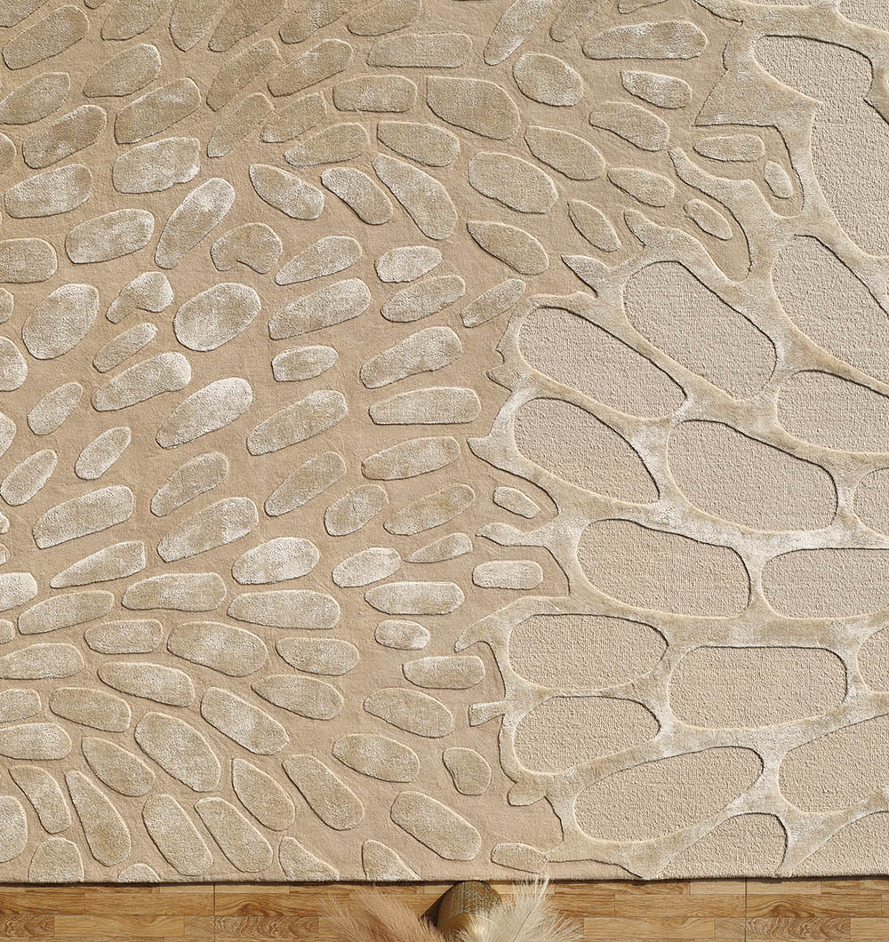 The Organic Flow Hand-Tufted Rug – Soothing Beige Textured Elegance HTWV-134 by RAMSHA HOME features irregular, natural stone-like shapes in beige and cream wool-viscose, adorned with a tassel and rests on a wooden floor.
