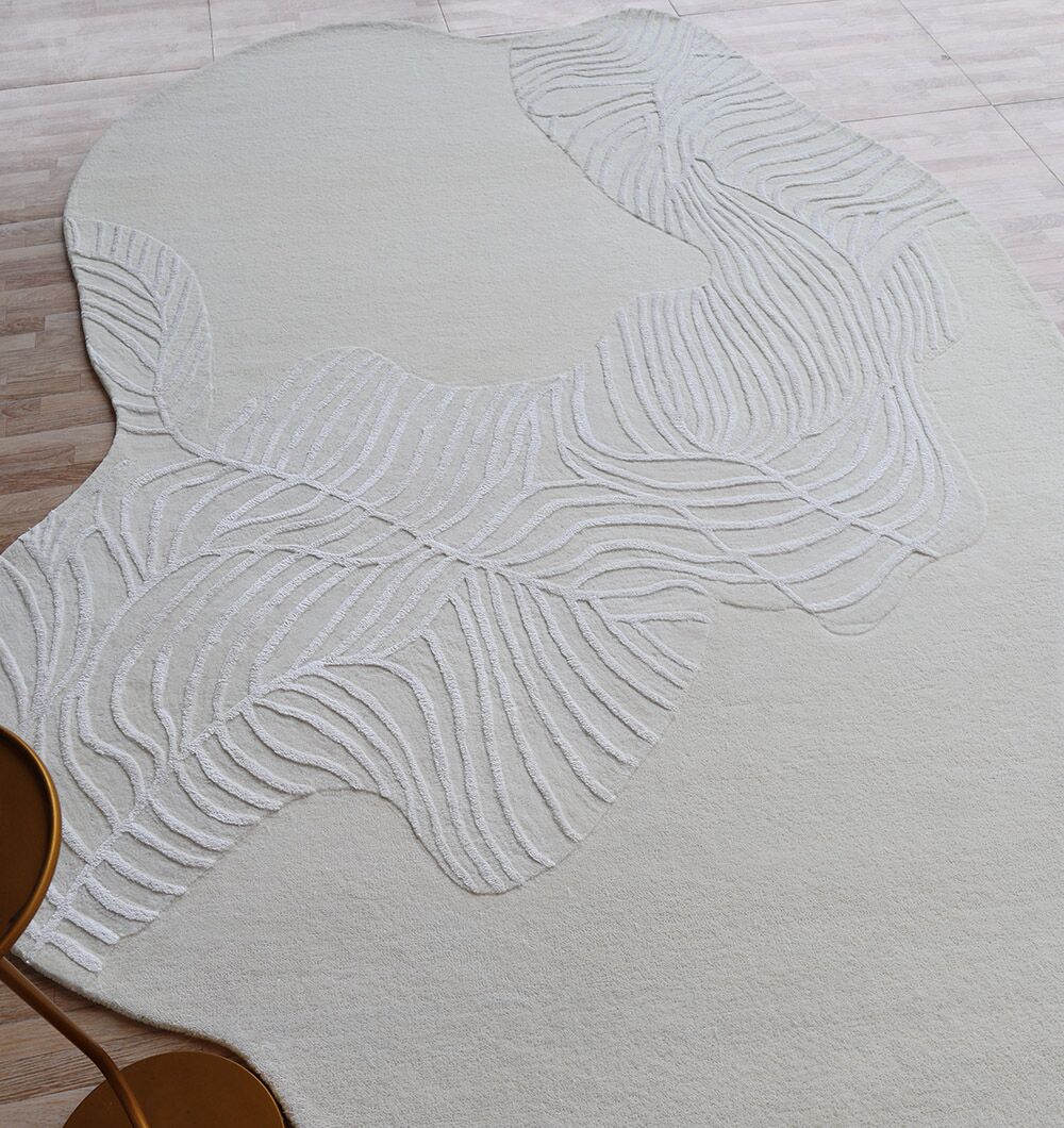 The Off White Color Handmade Area Rug - HTWV-140 (200x300 cm) by RAMSHA HOME, featuring organic wavy white patterns, rests on a light wood floor. Two round tan tables with slim legs appear in the corner.