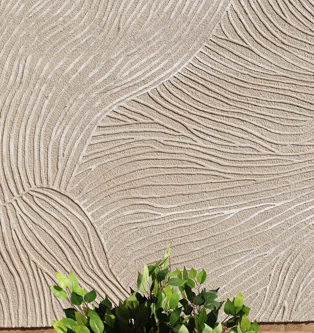 Close-up of the RAMSHA HOME Natural White Color Handmade Area Rug (HTWV-143, 300x400 cm) featuring wavy, carved lines and unique texture; green plant leaves at the bottom accentuate the rug’s design.