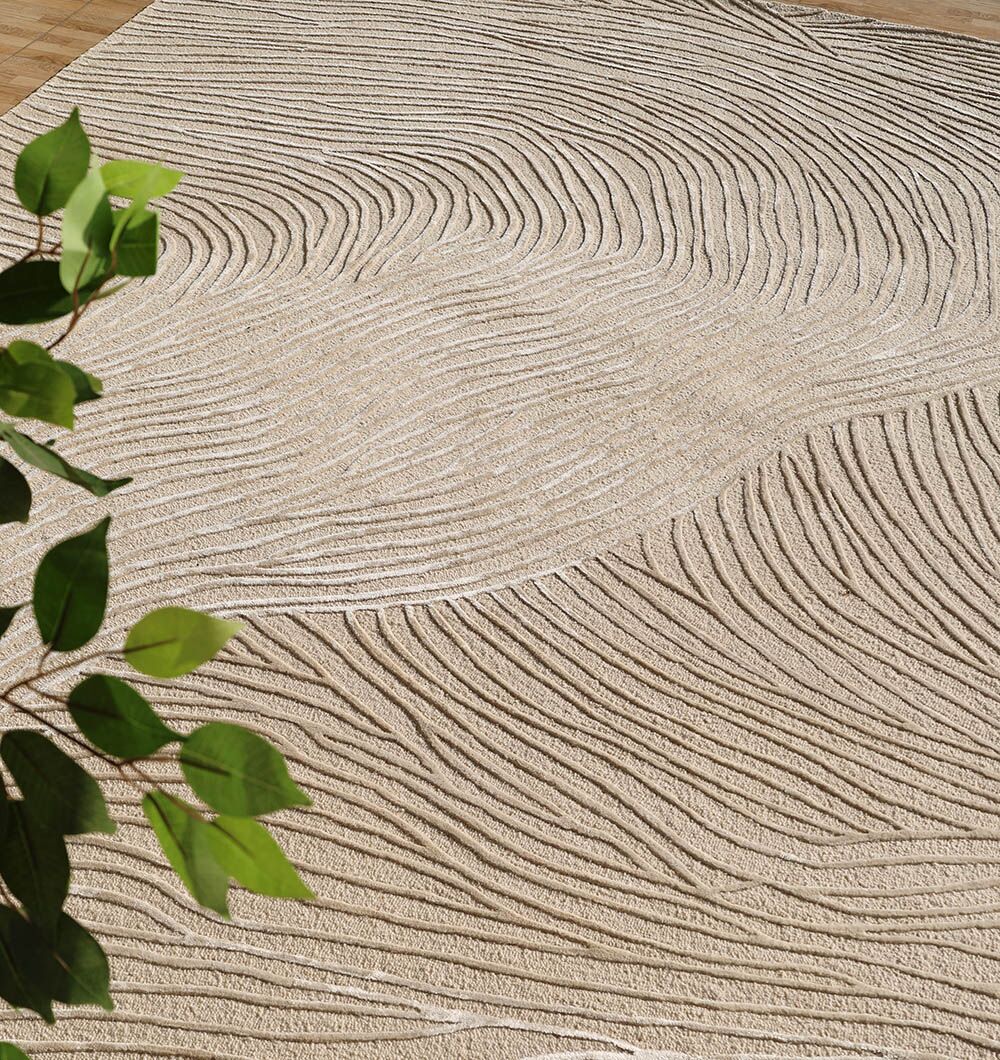 The RAMSHA HOME Natural White Color Handmade Area Rug (HTWV-143, 300x400 cm) features wavy, raised lines for a sand dune-like look. Its textured pattern is complemented by nearby green leaves in the room.