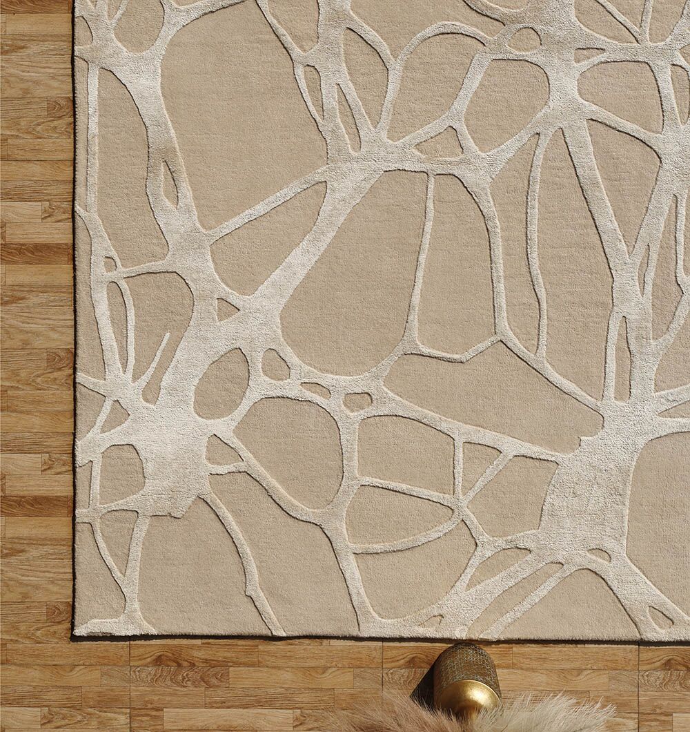 The Natural White Color Handmade Area Rug - HTWV-145 (200x300 cm) by RAMSHA HOME, a modern wool rug with an abstract web-like pattern, is displayed on a light wood floor, styled with a round gold table and a beige accent.