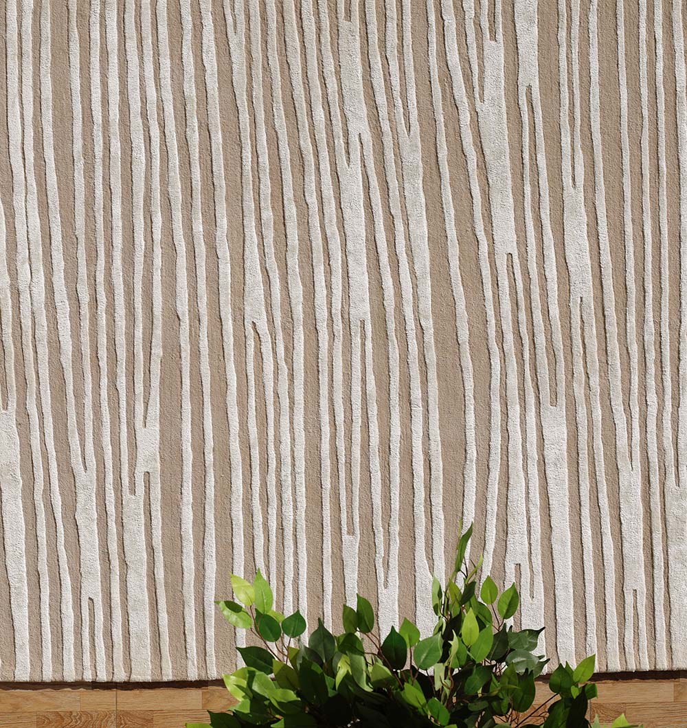 A beige and white textured wall with tree-bark-like lines rises above green leafy branches that partially cover the RAMSHA HOME Natural Color Handmade Area Rug (HTWV-147, 300x400 cm), its neutral stripes echoing the natural tones.