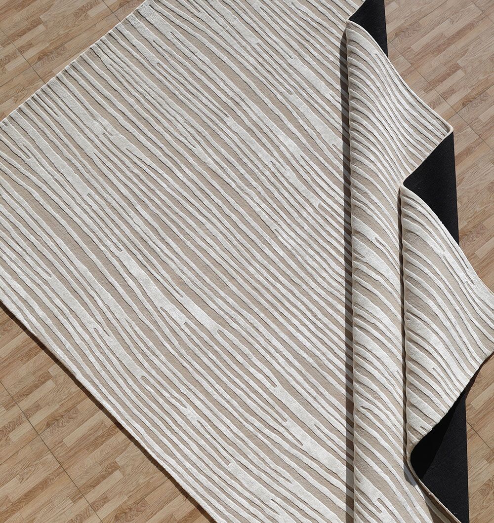 The RAMSHA HOME Natural Color Handmade Area Rug - HTWV-147 (300x400 cm) features a beige and white wood grain pattern, is handtufted from wool, and is shown partially folded to reveal its black underside on a light wood floor.