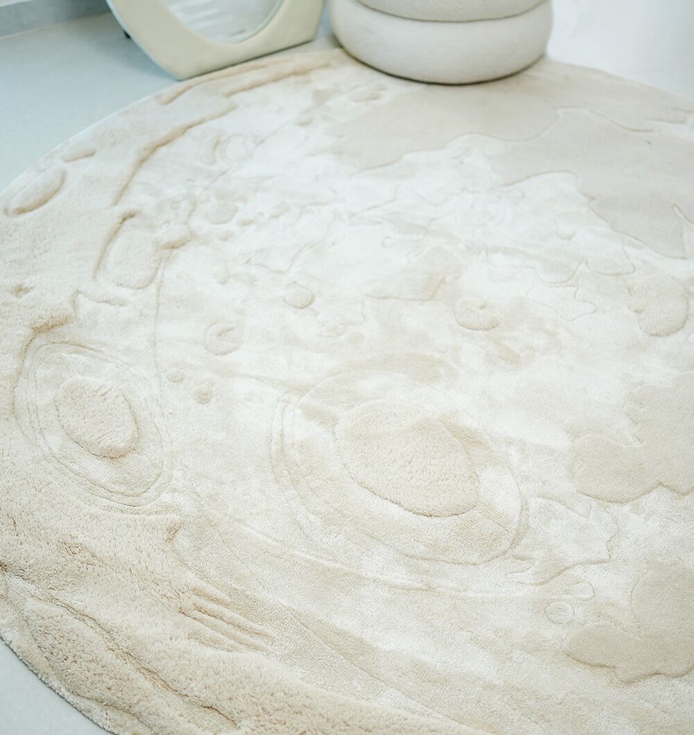 The RAMSHA HOME Natural Color Handmade Area Rug - HTWV-150 (200 cm) is a round, cream wool rug with a textured, crater-like raised pattern, shown on a light floor beside a white chair.
