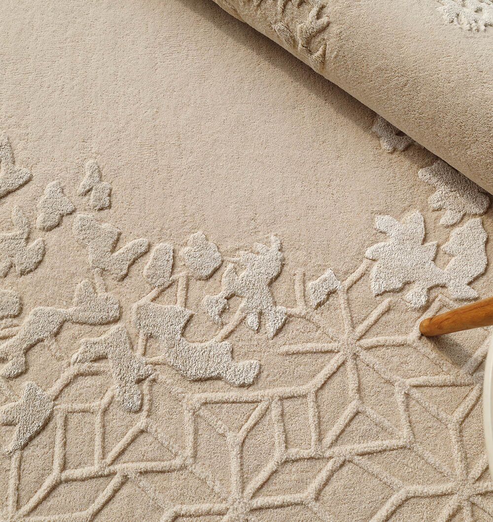 A close-up of the RAMSHA HOME Natural Color Handmade Rug - HTWV-151 (200 cm), featuring beige wool-viscose, geometric star and floral patterns, raised 3D details, and a visible rolled edge at the top.
