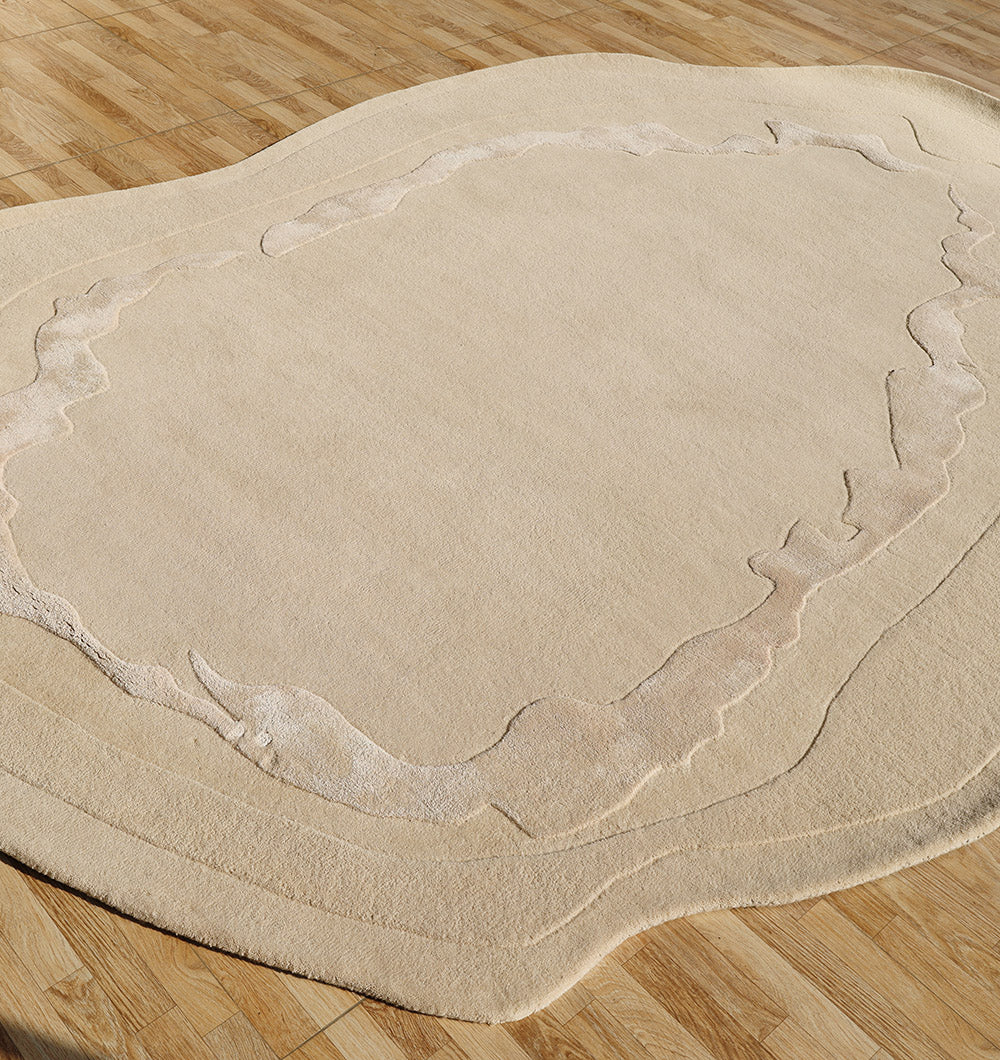 The RAMSHA HOME Premium Beige Handmade Carpet HTWV-155 (200×300 cm) features hand-tufted wool in an irregular shape with layered, wavy outlines, its textured surface on the wood floor evoking a natural or topographical form.