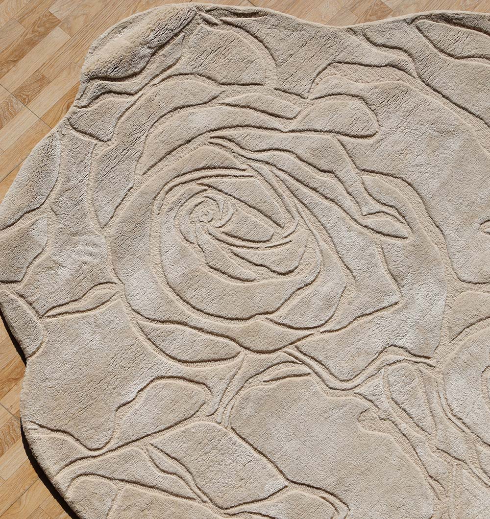 The RAMSHA HOME Handmade Area Rug (HTWV-156) features elegant floral designs and embossed rose patterns, adding detailed carved textures to your space, as seen on this beige rug laid over a light wooden floor.
