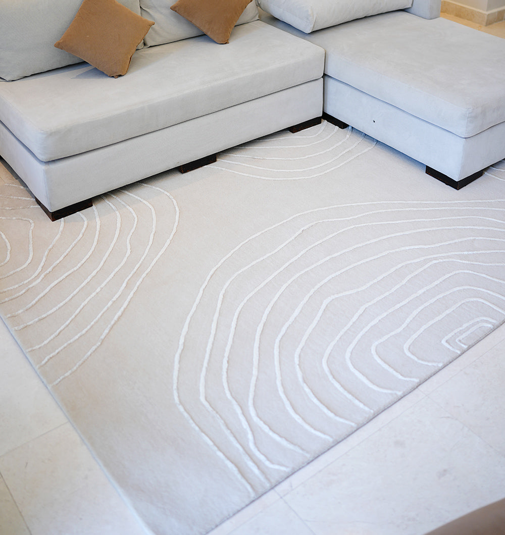 A modern light-colored sectional with brown accent pillows sits on the Handmade Home Decor Area Rug – HTWV-157 by RAMSHA HOME, featuring subtle topographic-style lines, adding minimalist and cozy charm to the room.