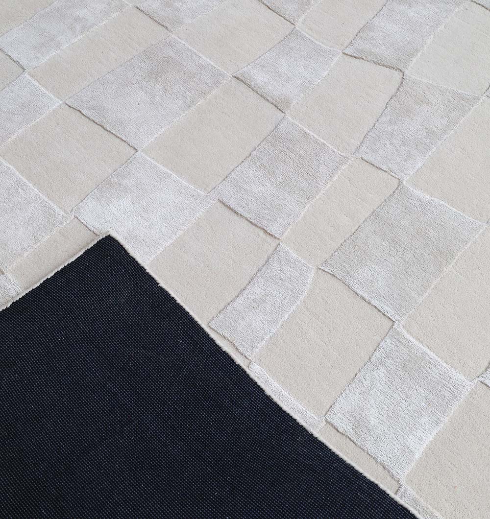 The RAMSHA HOME Light Beige Color Handmade Carpet – HTWV-159 features a modern, irregular patchwork design and a solid black underside. This viscose blend rug offers a soft, luxurious feel and stylish contemporary appeal.