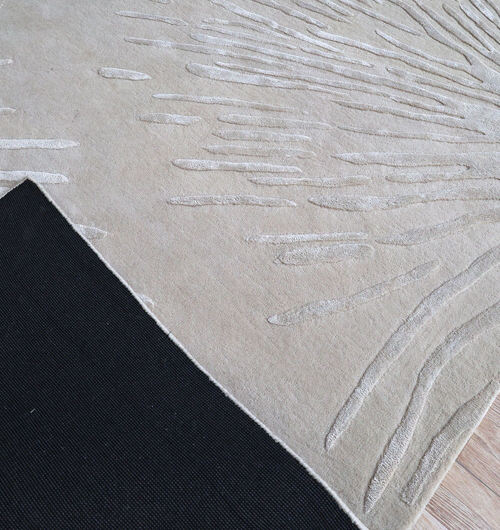 A close-up of RAMSHA HOME's Rectangle Home Decor Light Beige Color Rug - HTWV 160 (300x400 cm), hand tufted with raised abstract patterns, partially lifted at one corner to show a black rug pad beneath on a wooden floor.