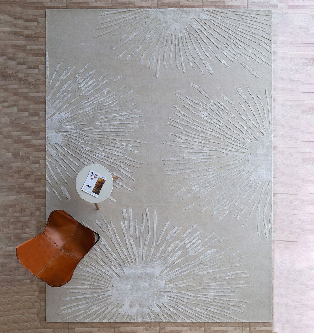 The RAMSHA HOME Rectangle Home Decor Light Beige Color Rug - HTWV 160 (300x400 cm) features abstract radiating white lines and sits on a light wood floor, with a small round table and brown leather chair in the corner of this hand-tufted piece.