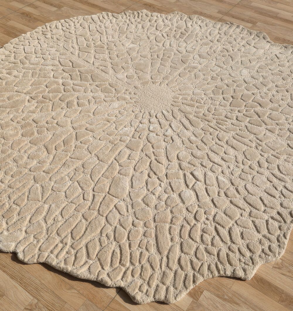 The Shaped Area Handmade Rug - HTWV 162 (200 cm) by RAMSHA HOME is a round, hand-tufted wool rug featuring an irregular organic edge and stone-like textured pattern, displayed on a wooden floor.