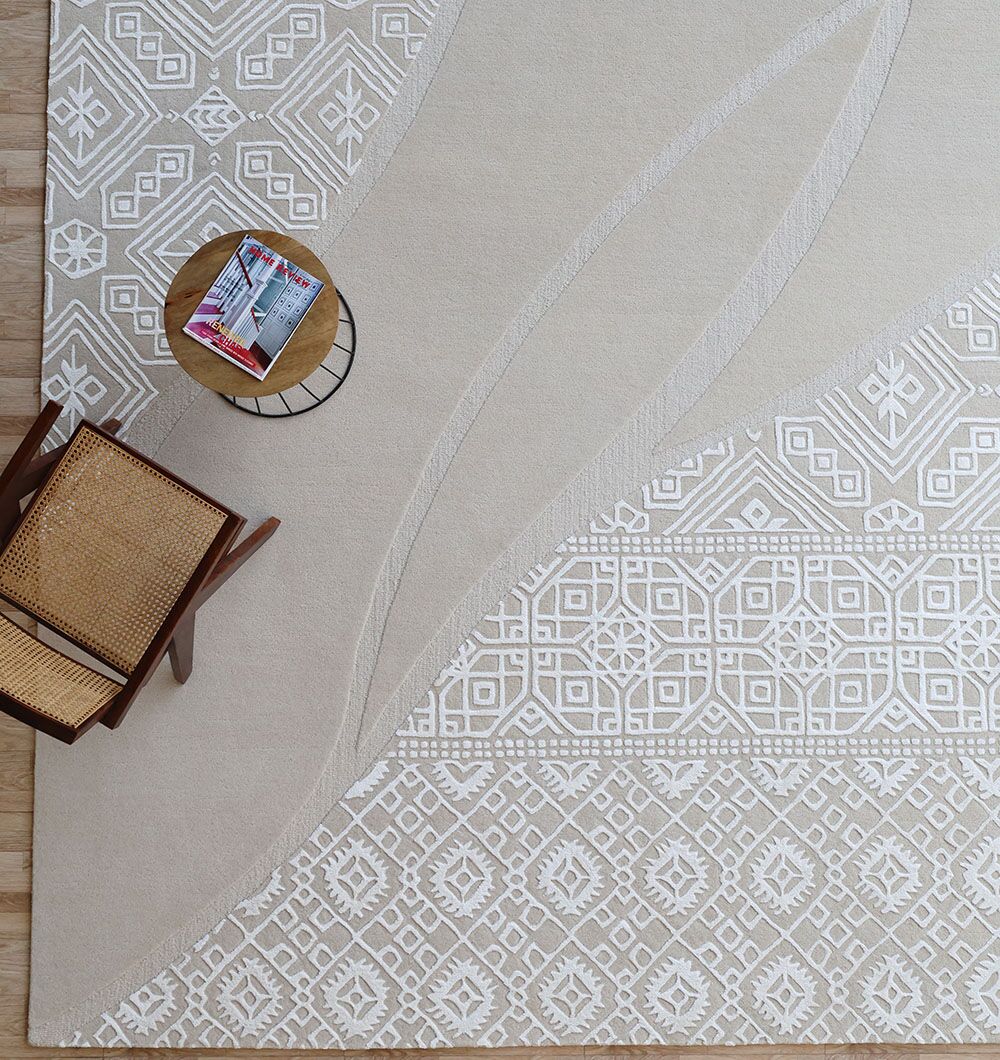 The Boho Geometric Handmade Decorative Area Rug - HTWV 167 (300x400 cm) by RAMSHA HOME lies on the floor, topped with a wooden chair and round side table holding a magazine in its stylish top left corner.