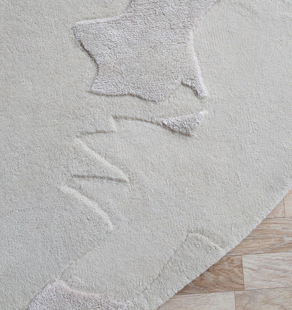 A close-up of the RAMSHA HOME Round Home Decor Handmade Rug - HTWV 170 (200 cm), showcasing its neutral tones and raised abstract patterns on a light wood floor, with subtle variations in height and texture for visual interest.