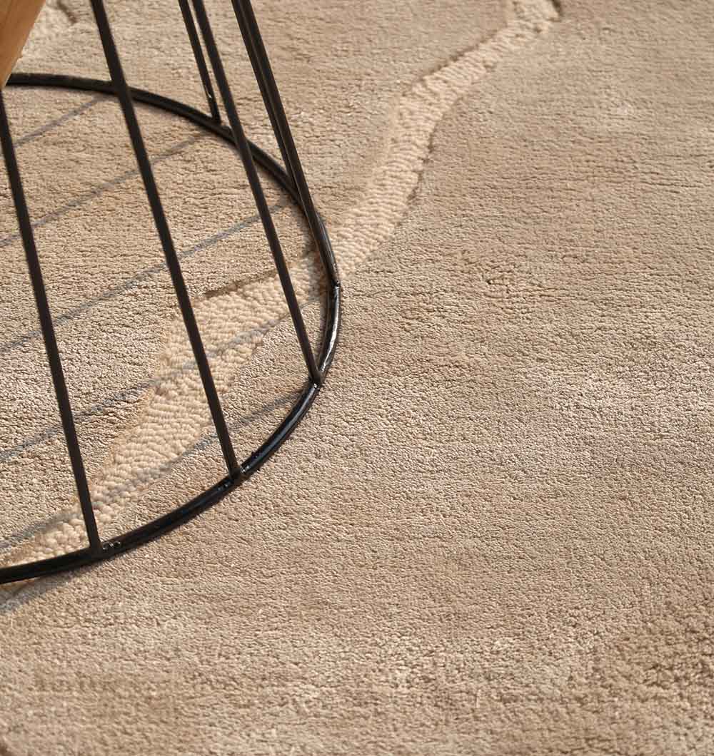 A close-up of the RAMSHA HOME Modern Viscose & Wool Handmade Carpet 200x300 (HTWV-172) in beige shows a water stain and part of a black metal furniture leg in the corner.