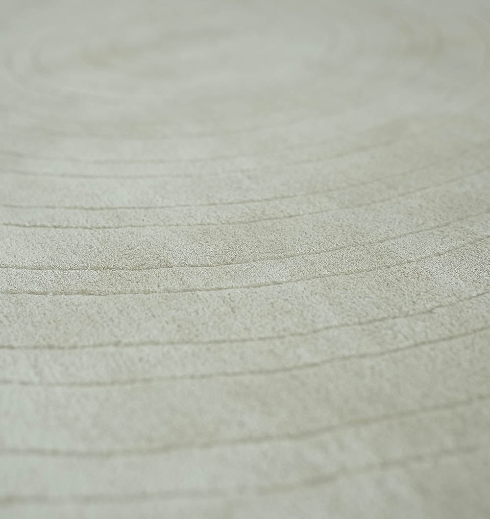 Close-up of the RAMSHA HOME Decorative Handmade Modern Shaped Rug HTWV 185 (183 x 200 cm), featuring a pale beige hue and subtle concentric circular lines, evoking tree rings or a raked sand pattern.