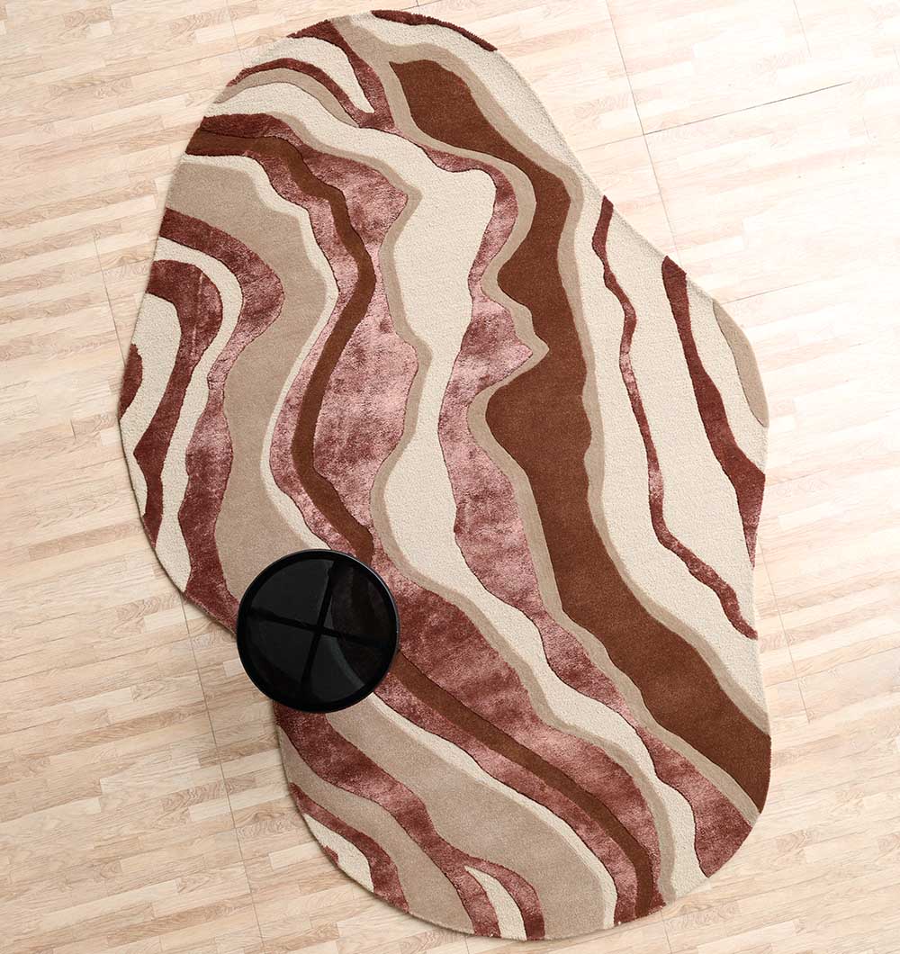 The RAMSHA HOME Decorative Handmade Multi Color Shaped Area Rug – HTWV 187 features abstract wavy brown, beige, and pink lines, shown on a light wood floor with a round black table partially atop this modern neutral rug.