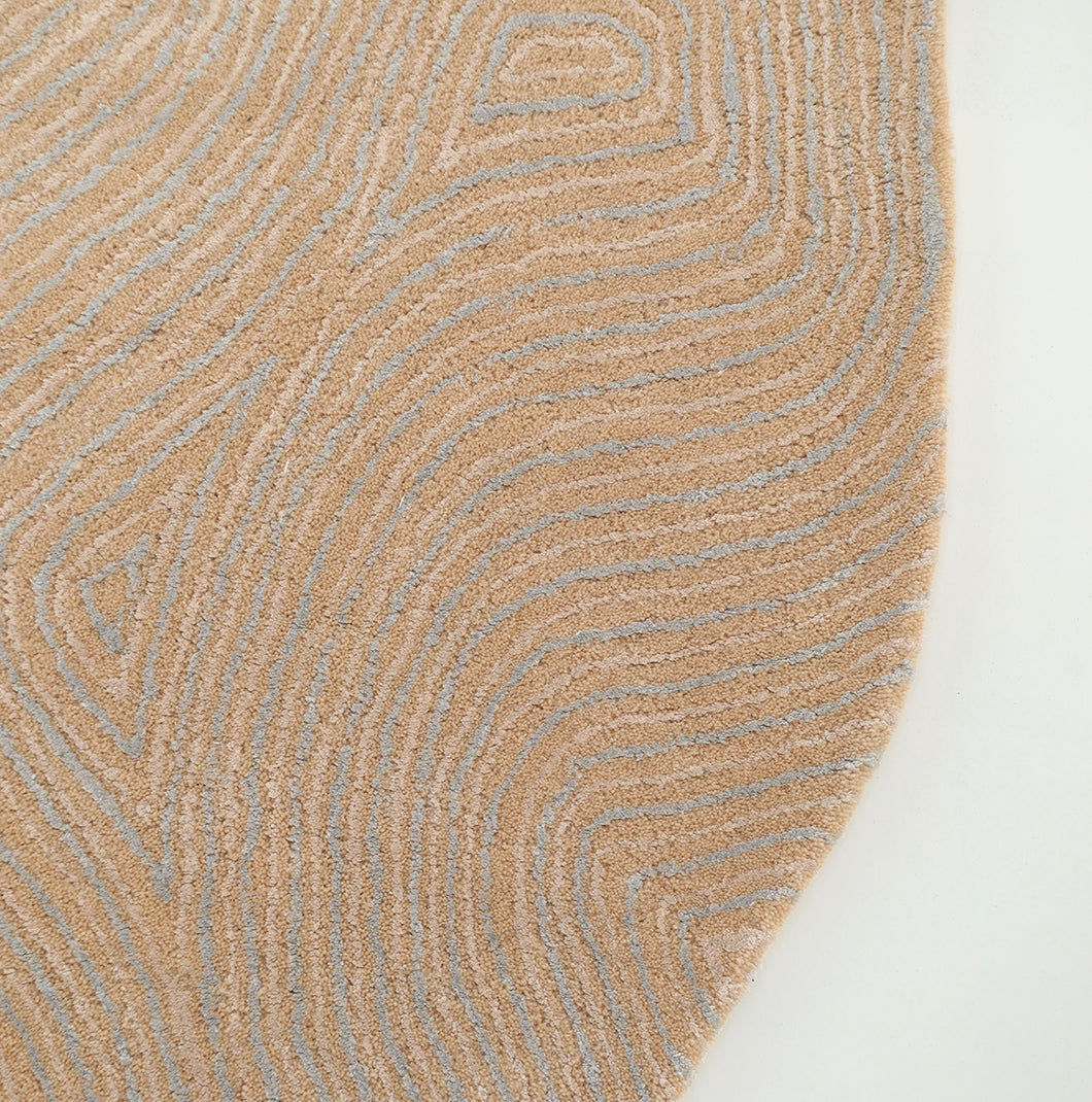 A close-up of the RAMSHA HOME Handmade Beige Abstract Shaped Rug 200 cm HTWV-188, featuring organic curves in beige with light gray wavy, concentric line patterns, hand-tufted to form a striking abstract design, displayed against a plain white background.