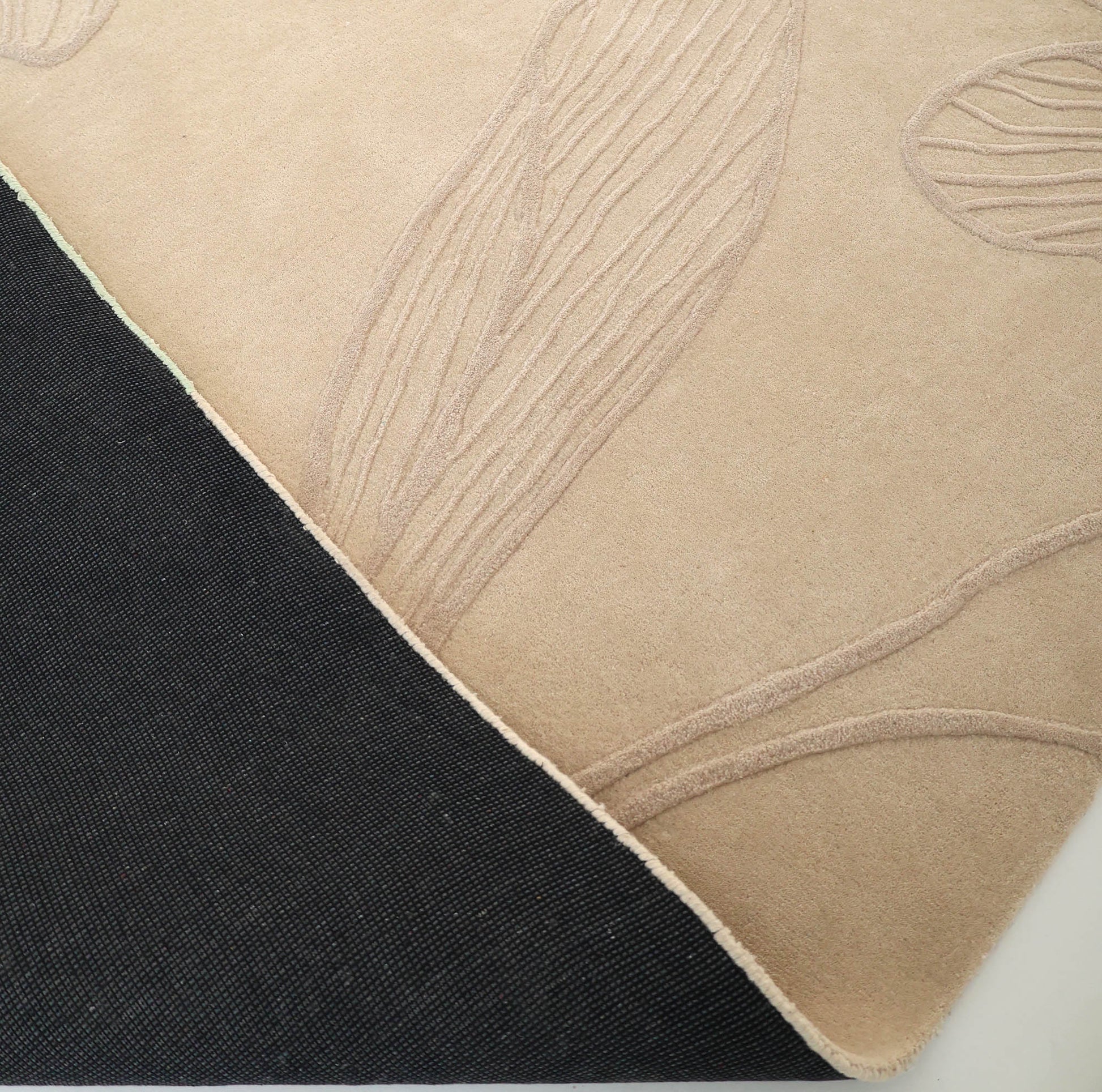 A close-up of RAMSHA HOME's Floral Handmade Rectangle Rug HTWV-189 shows its beige, raised leaf patterns and textured black underside—a stunning example of artisanal craftsmanship.