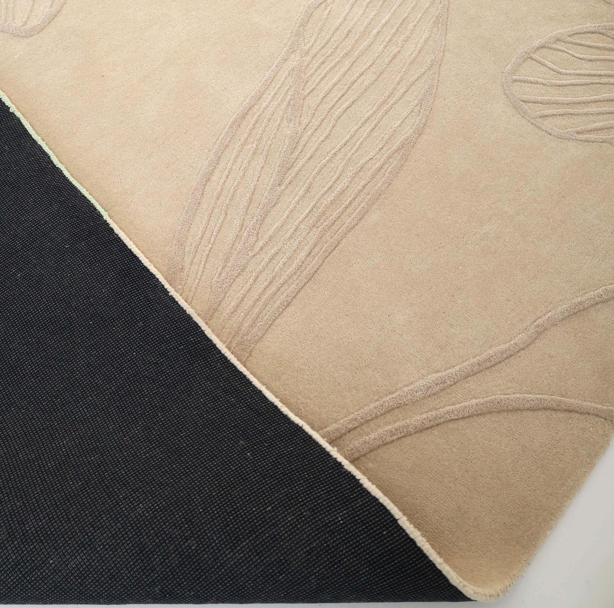 A close-up of RAMSHA HOME's Floral Handmade Rectangle Rug HTWV-189 shows its beige, raised leaf patterns and textured black underside—a stunning example of artisanal craftsmanship.
