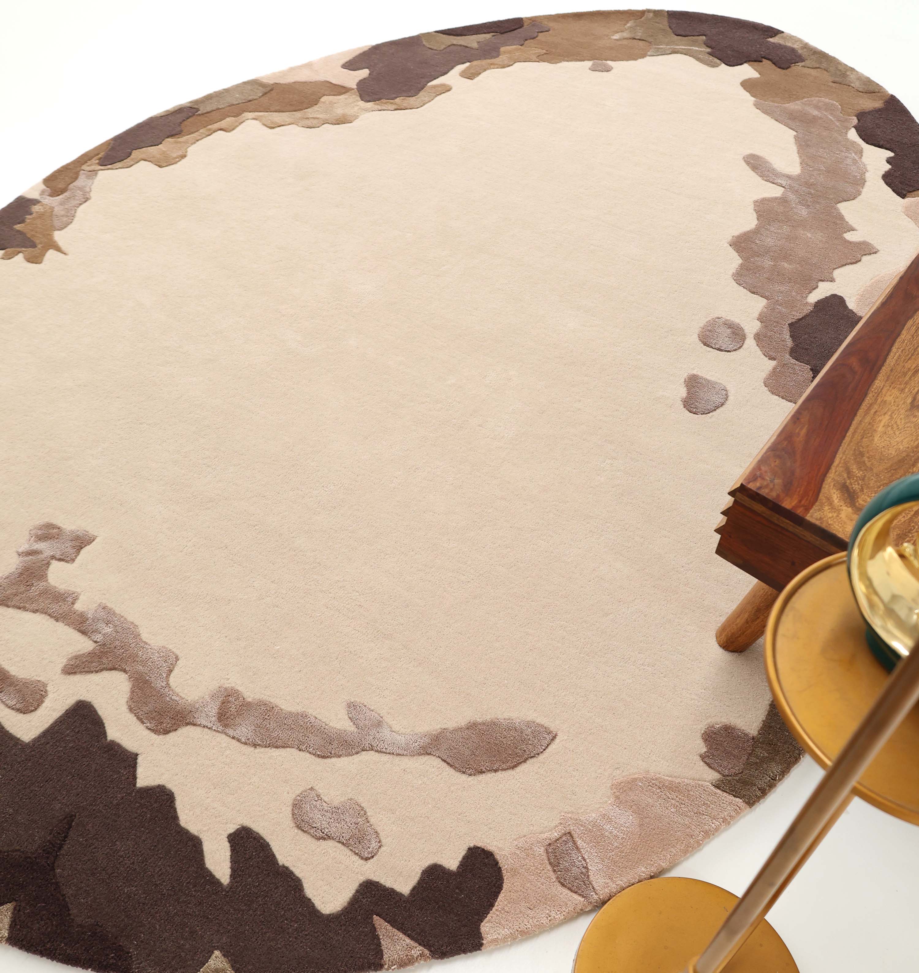 The RAMSHA HOME Terra Eclipse Oval Handmade Rug HTWV-195 features a beige center with brown, taupe, and tan borders, adding warmth beside wooden tables and gold round side tables on a white floor.