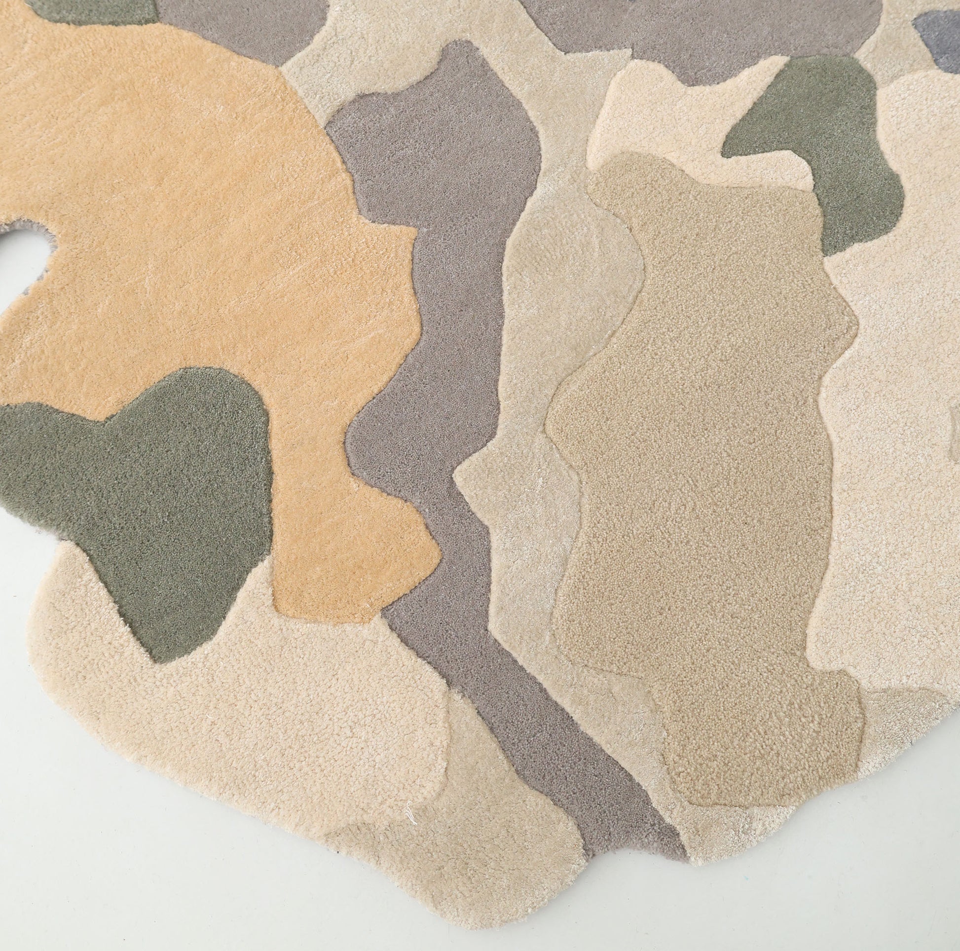 A close-up of the RAMSHA HOME Contemporary Flow Area Handmade Rug HTWV-199 shows its abstract oval shape and camo-inspired beige, tan, olive green, and gray tones—ideal for adding modern flair to any interior.