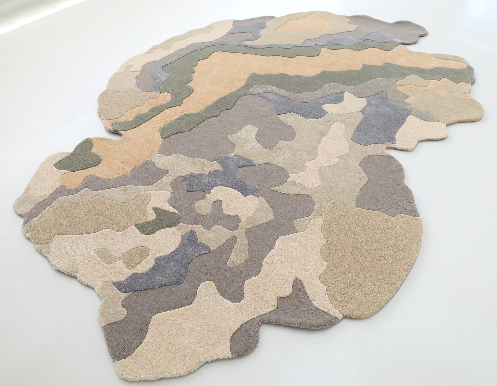 The RAMSHA HOME Contemporary Flow Area Handmade Rug HTWV-199, with an abstract camouflage pattern in beige, tan, gray, and muted green, is spread on a white floor.
