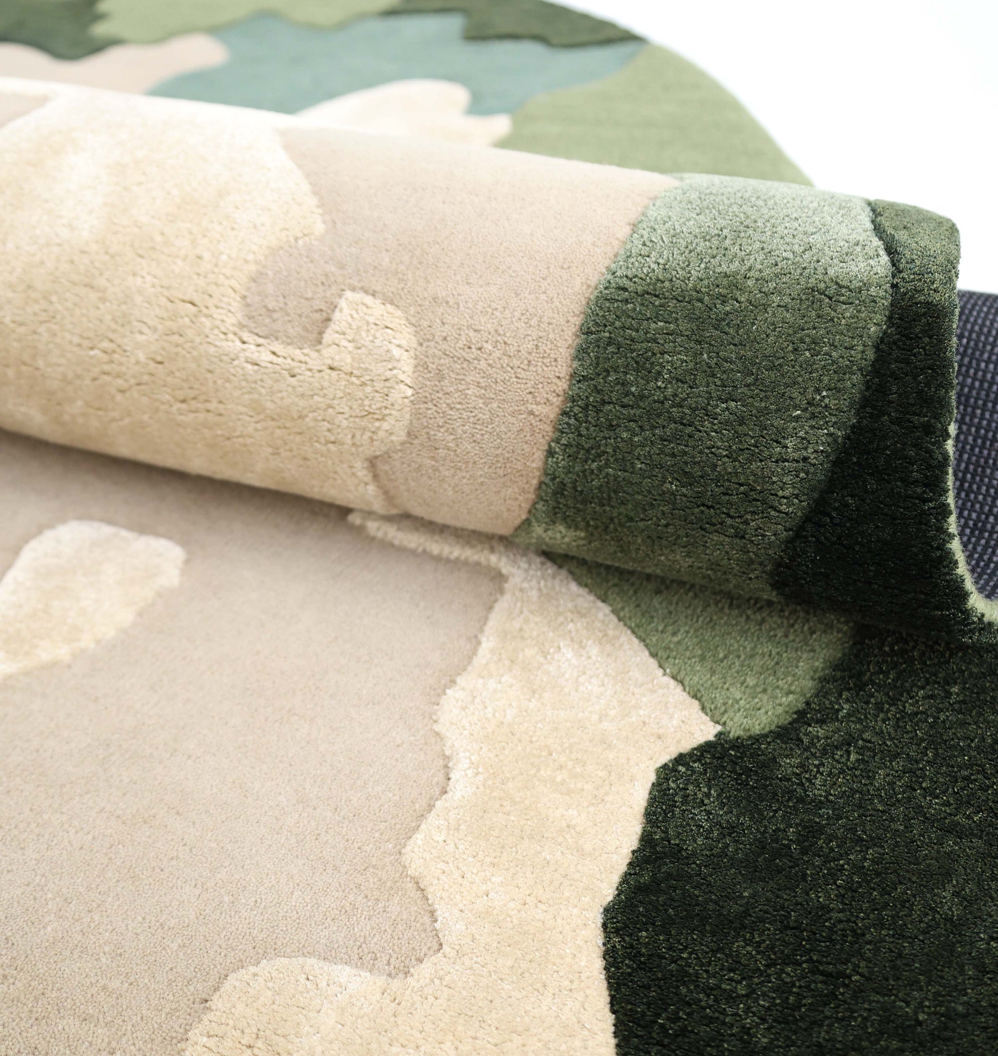 A close-up of the RAMSHA HOME Terra Eclipse Oval Handmade Rug Accent Rug HTWV-201, showcasing its camouflage pattern in beige, tan, green, and dark green on a light background.