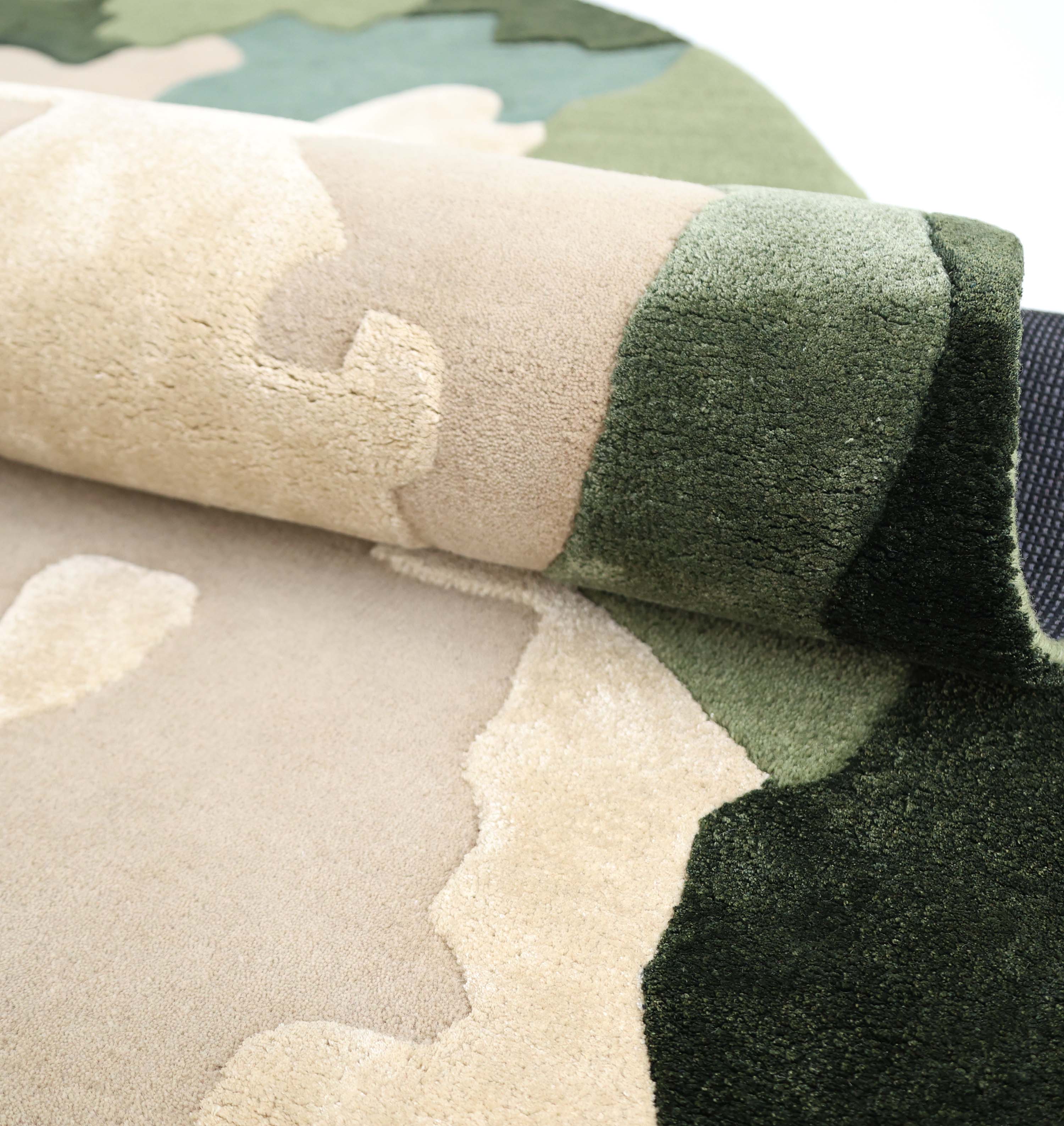 A close-up of the RAMSHA HOME Terra Eclipse Oval Handmade Rug Accent Rug HTWV-201, showcasing its camouflage pattern in beige, tan, green, and dark green on a light background.