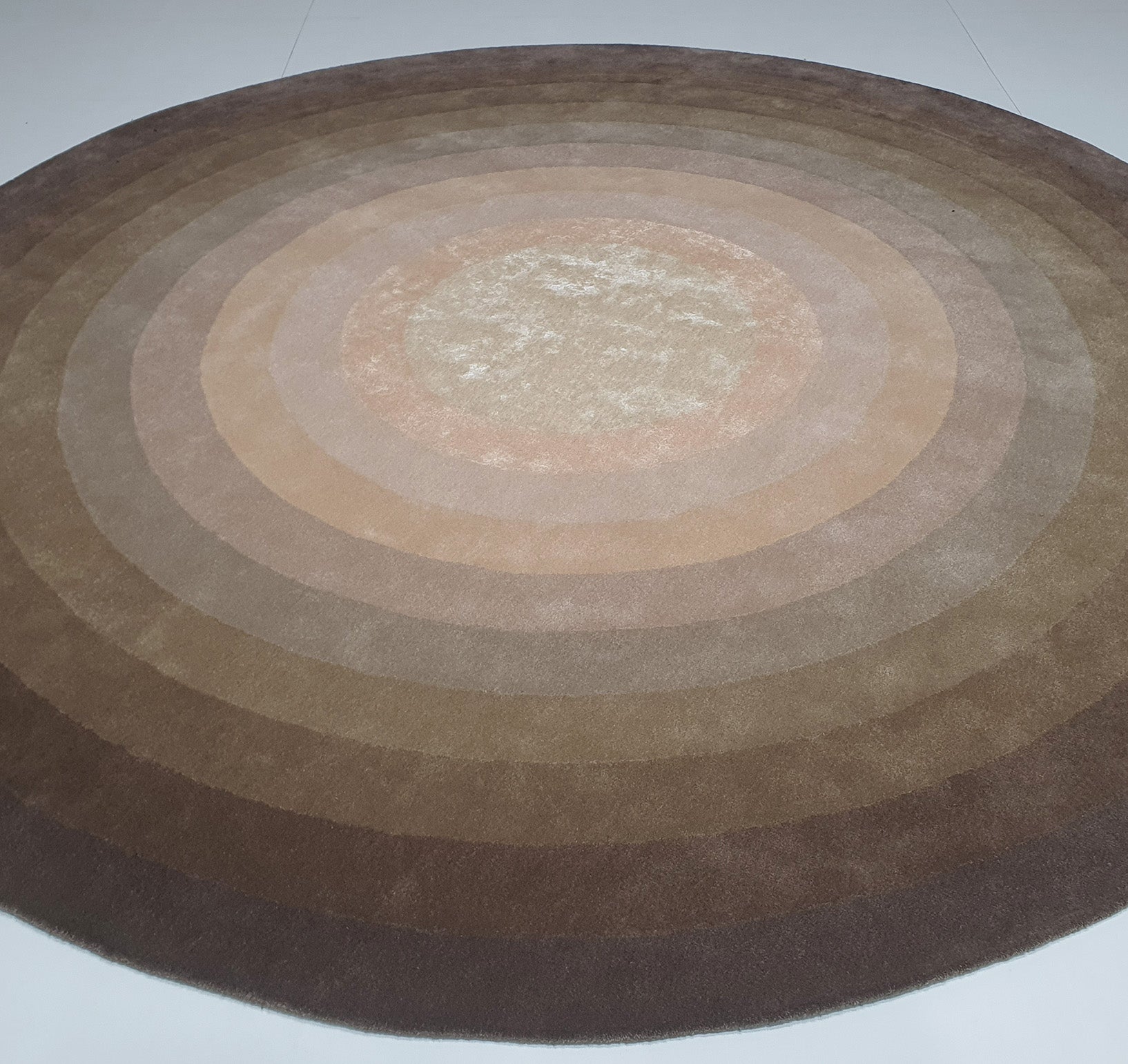 The Wool & Cotton Handmade Round Rug - HTWV 54 (300cm) by RAMSHA HOME features concentric rings in brown, beige, and tan, creating a warm, stylish accent for any light-colored floor.
