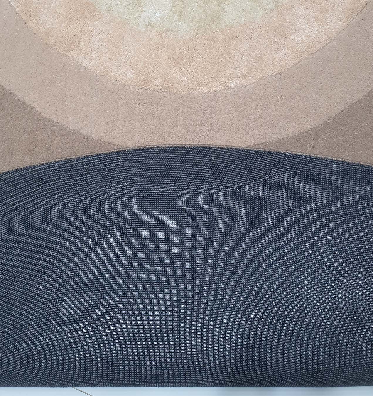 Close-up of the RAMSHA HOME Wool & Cotton Handmade Round Rug - HTWV 54 (300cm), featuring overlapping arcs in beige, tan, brown, and textured dark gray. This modern geometric design is ideal for contemporary round rug decor.