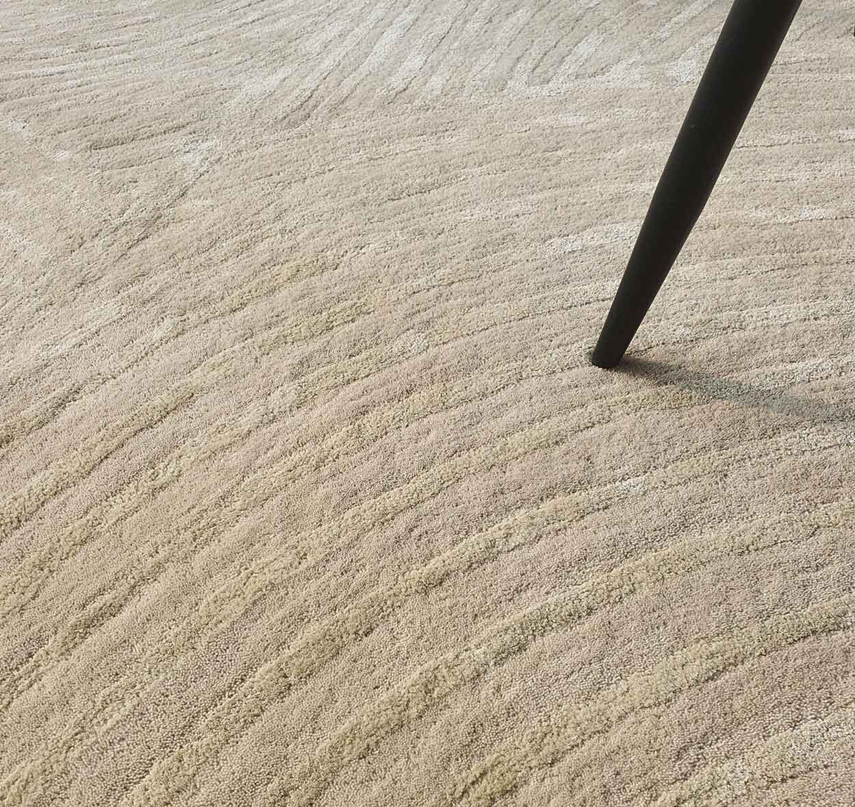 A close-up of the RAMSHA HOME Luxurious Wool & Cotton Rug - HTWV 71 (300x400cm), showcasing its textured ivory surface with wavy patterns and a single black tapered furniture leg in the upper right corner.