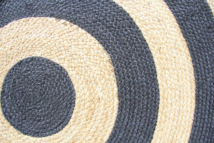 Close-up of the RAMSHA HOME Handmade Braided Jute Floor Round Rug - BR 058 (200cm), featuring bold black and natural beige spiral stripes in a geometric pattern. The jute fiber texture is distinctly visible.