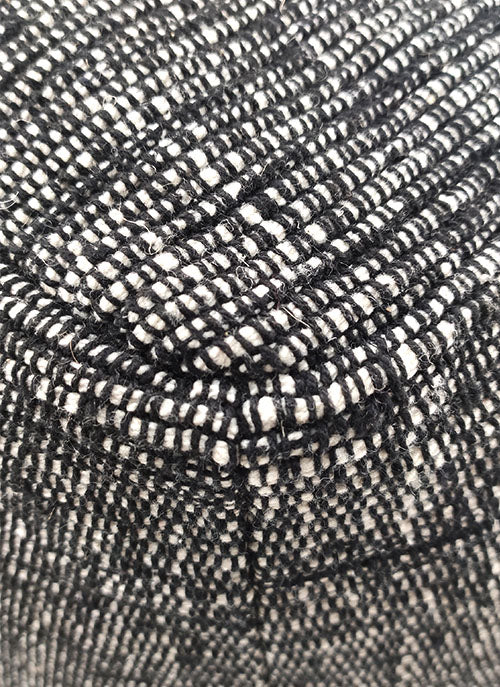 Close-up of the RAMSHA HOME Black Cotton Pouf With Leather Handle PF-046, highlighting its detailed black and white woven fabric, intersecting threads, and prominent seam—showcasing stylish texture ideal for modern seating.