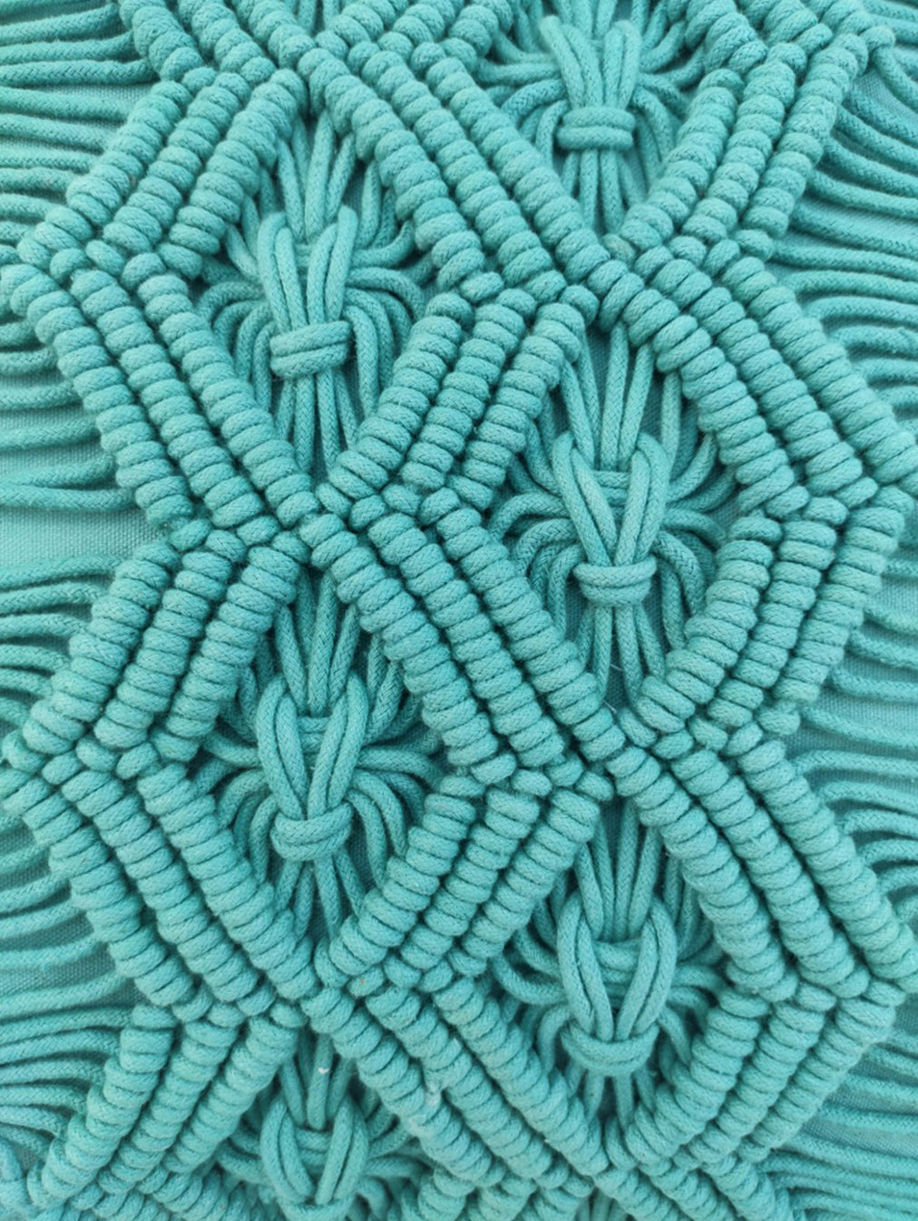 Close-up of an intricate turquoise macrame pattern with diamond shapes and textured woven cords, featured on the RAMSHA HOME Macrame Cotton Cushion With Filler—ideal for adding a unique accent to your home decor.