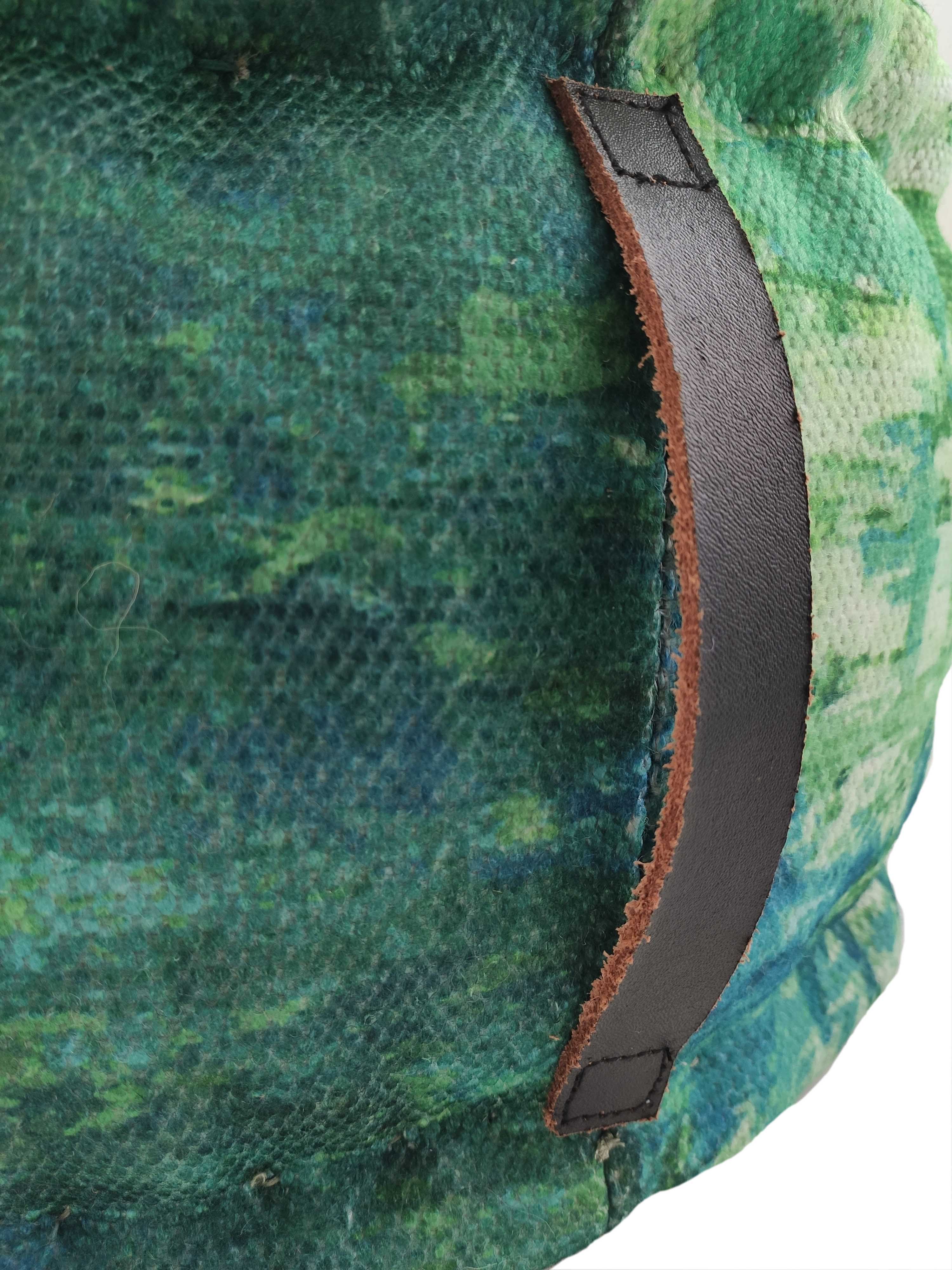 Close-up of a green and blue textured fabric with a brown leather handle, part of the RAMSHA HOME Printed Multi Color Pouf With Leather Handle.