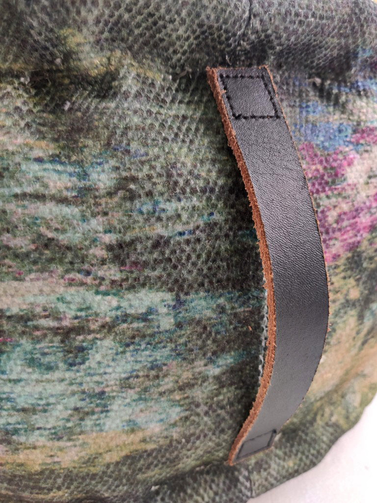 Close-up of the RAMSHA HOME Printed Multi Color Pouf With Leather Handle, showcasing its vibrant textured fabric and sturdy black leather handle.