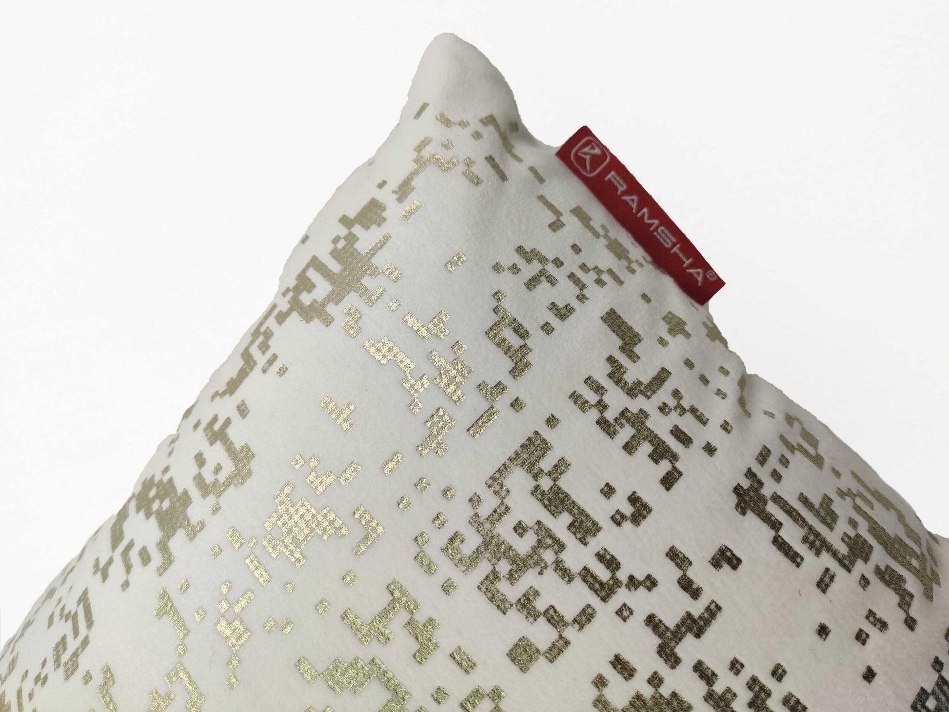 A close-up of the White Cushion CS-097 by RAMSHA HOME showcases its gold pixelated pattern and red tag, blending style and comfort with a high-density filler.